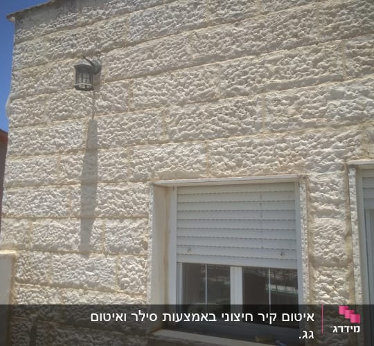 קיר אבן עם חלונות ותריסים סגורים